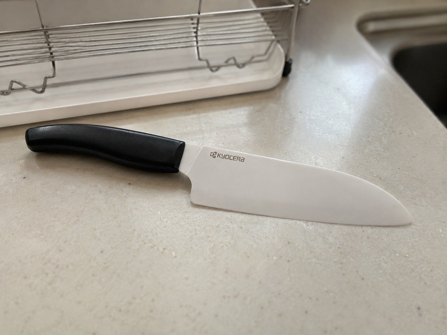 A Kyocera ceramic santoku knife after ten years of use, with a white blade and black handle